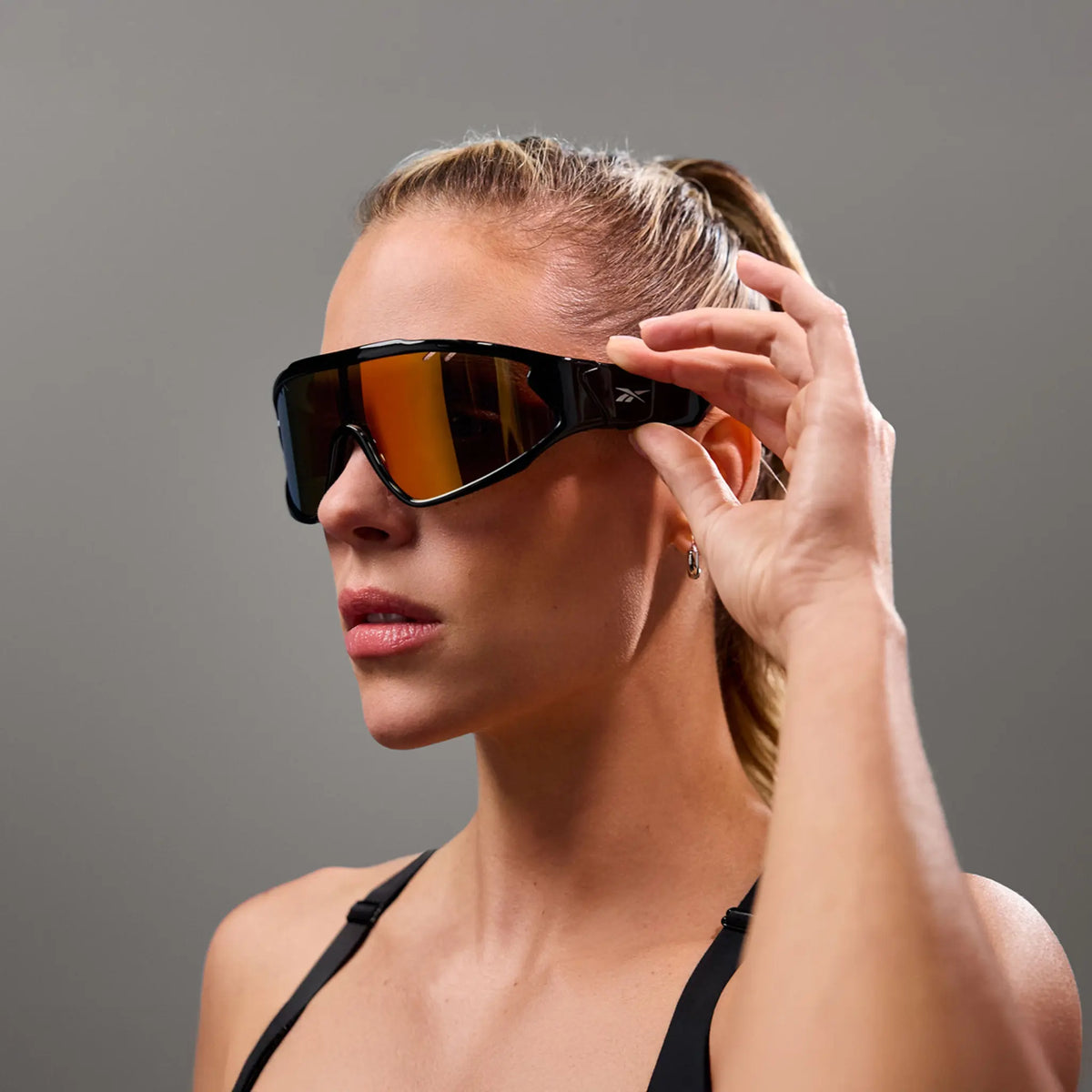 Woman touching the temple of Reebok Voltage red mirror sunglasses